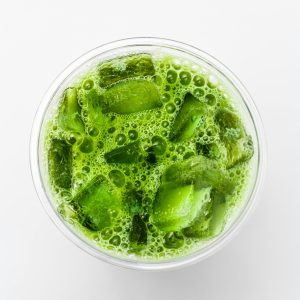 Top-down shot of a refreshing iced matcha latte with vibrant green color and ice cubes.